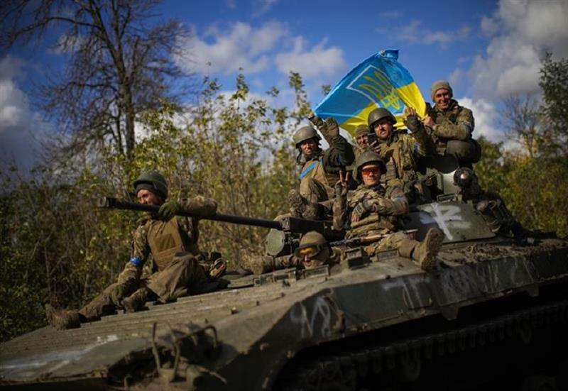 Ukrainian soldiers sit on an armoured vehicle as they drive on a road between Izium and Lyman in Ukr