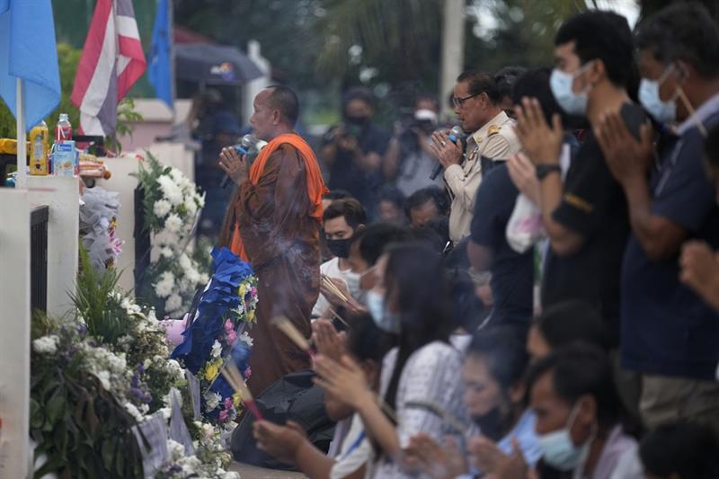 Buddhist pray with relatives of the victims of a mass killing attack in front on the Young Children 