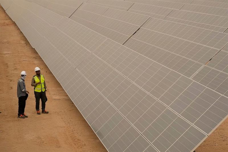 Engineers talk next to photovoltaic solar panels at Benban Solar Park, one of the world s largest so