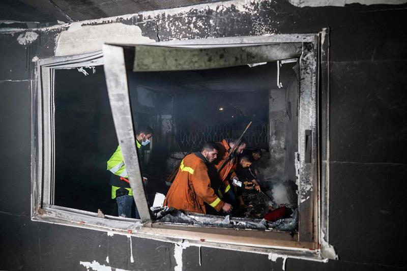 Palestinian firefighters extinguish flames in an apartment ravaged by fire in the Jabalia refugee ca