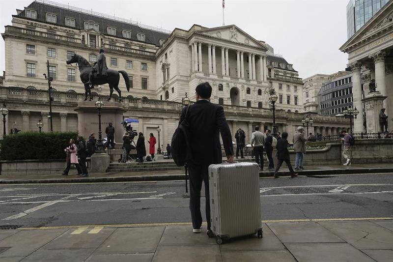A man stands in front of the Bank of England, at the financial district in London