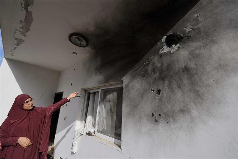 A Palestinian woman points at holes on her wall caused by the storm of the house by the Israeli army