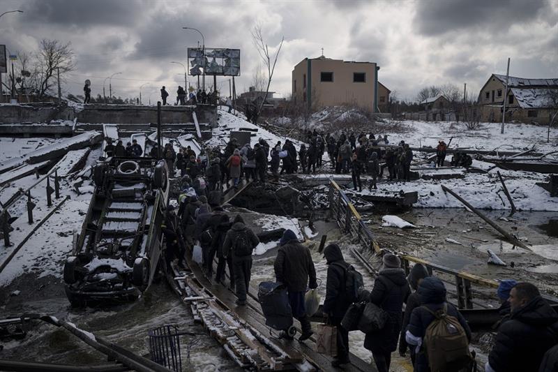 Ukrainians cross an improvised path under a destroyed bridge while fleeing Irpin, in the outskirts o