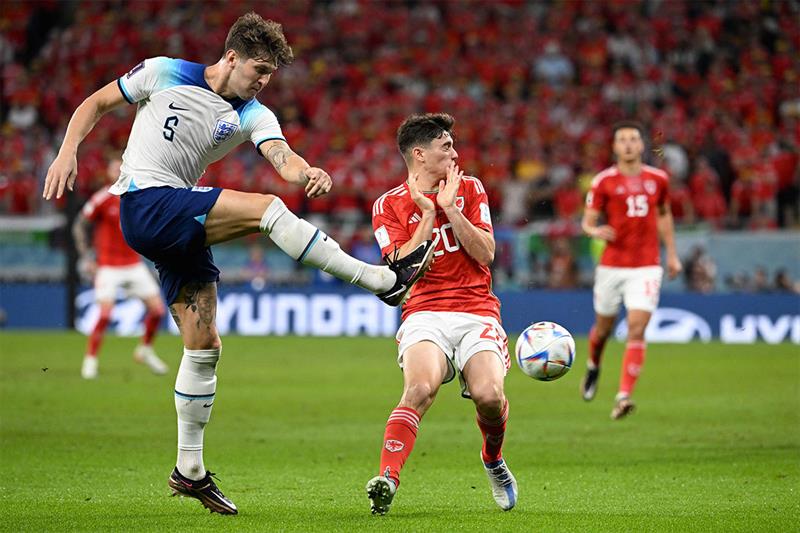 England s defender #05 John Stones (L) kicks the ball as Wales  forward #20 Daniel James (R) reacts 