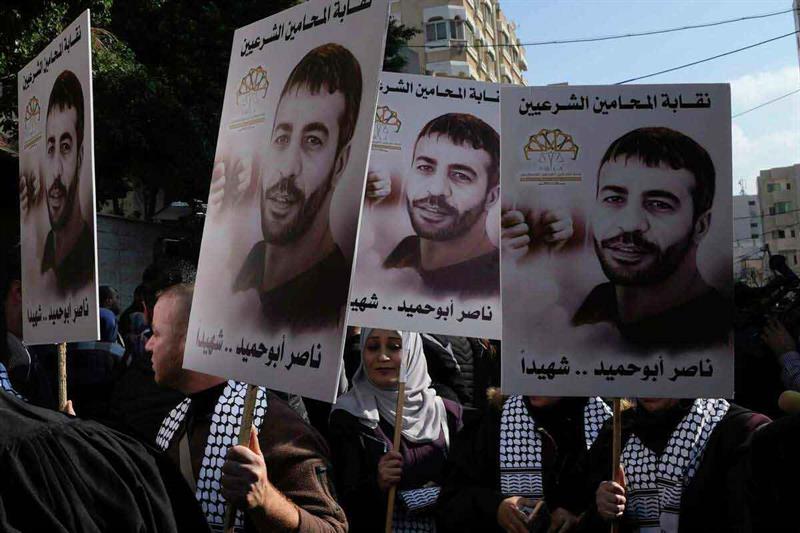 Palestinians hold posters of Palestinian prisoner Nasser Abu Hamid during a protest in front of the 