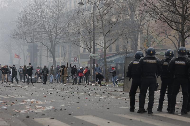 Demonstrators throw stones toward police officers during a protest against the recent shooting at th