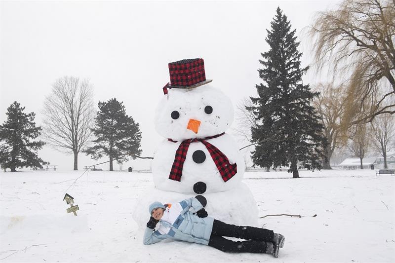 Alya Eren (11) poses beneath a snowman in Montreal, Sunday, Dec. 25, 2022. (Graham Hughes /The Canad
