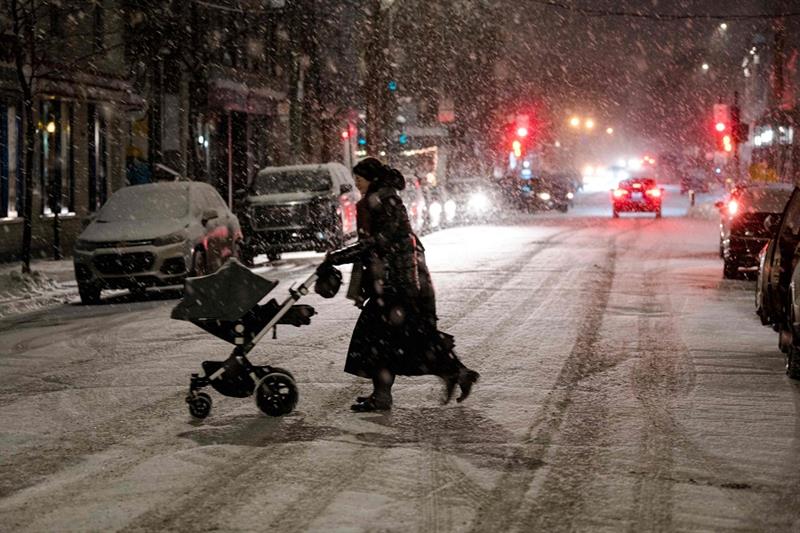 A person crosses a street in the Mile End, a borough in Montreal, Quebec, Canada, as the snow comes 