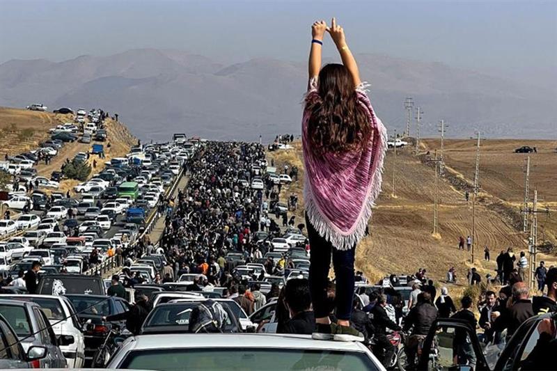 This UGC image posted on Twitter shows an unveiled woman standing on top of a vehicle as thousands m