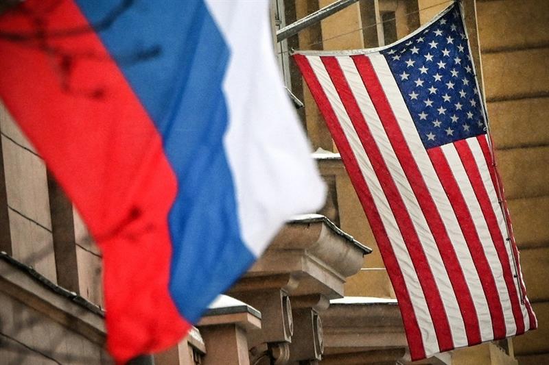 A Russian and US flag fly next to the US embassy building in Moscow