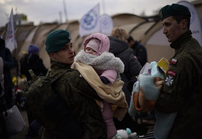 A Polish soldier holds a baby as refugees fleeing war in neighboring Ukraine arrive at the Medyka cr