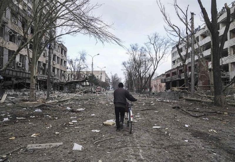 A man walks with a bicycle in a street damaged by shelling in Mariupol, Ukraine, Thursday, March 10,
