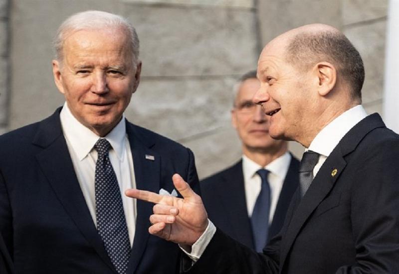 German Chancellor Olaf Scholz (R) gestures next to US President Joe Biden (L) as NATO Secretary Gene