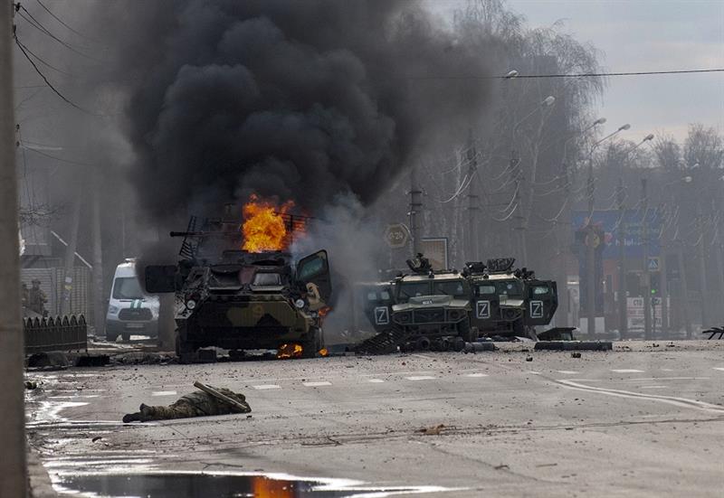 A Russian armored personnel carrier burns amid damaged and abandoned light utility vehicles after fi