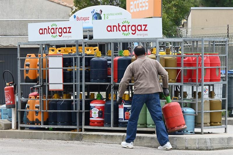 A person picks up a bottle of gas in France