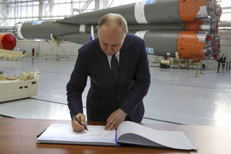 Russian President Vladimir Putin signs in the visitor s book at a rocket assembly factory during his