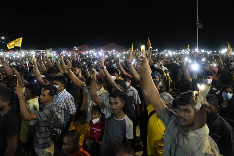 Sri Lankans hold up their mobile phone torches during a vigil condemning police shooting at proteste