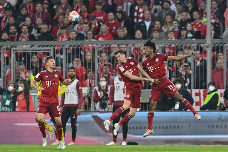 Bayern Munich s Polish forward Robert Lewandowski (C) jumps to head the ball next to Bayern Munich s