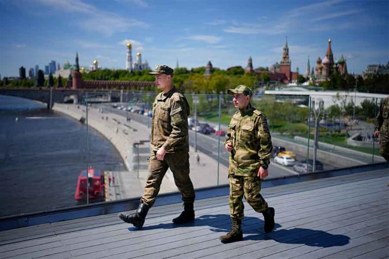 Russian soldiers walk on a bridge in Zaryadye Park, with Kremlin and St. Basil Cathedral in the back