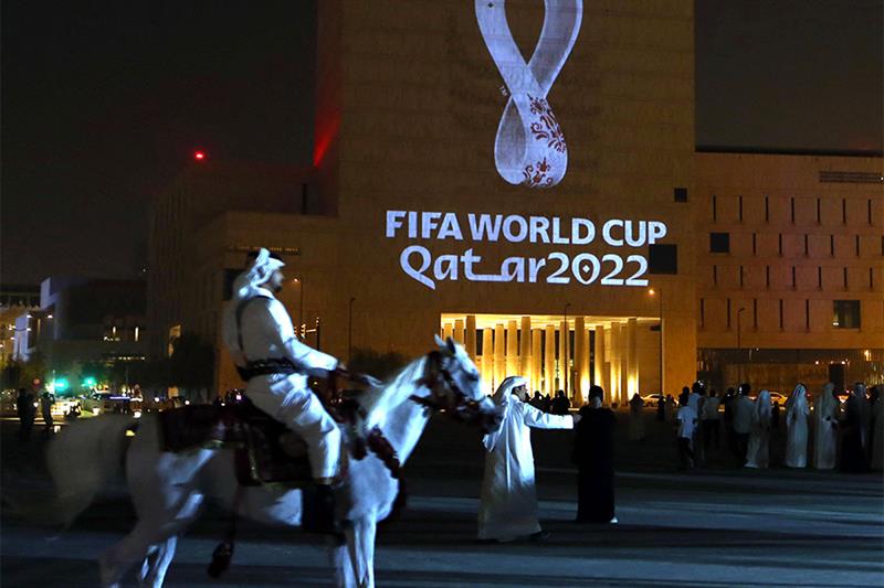  mounted policeman rides past a building on which the official logo of the FIFA World Cup Qatar 2022