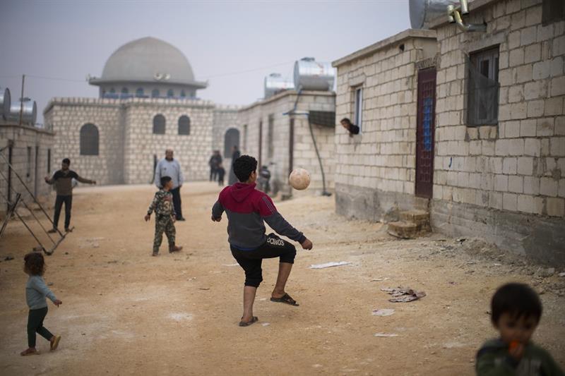Syrian children play with a ball in a refugee camp