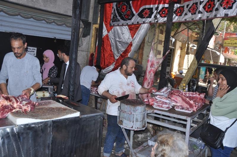a butcher cutting meat to customers in a meat shop in Al Sayeda Zeinab district, Cairo.