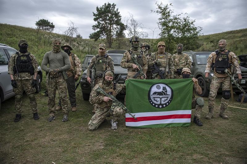 Volunteer soldiers pose with a flag of Chechen Republic of Ichkeria
