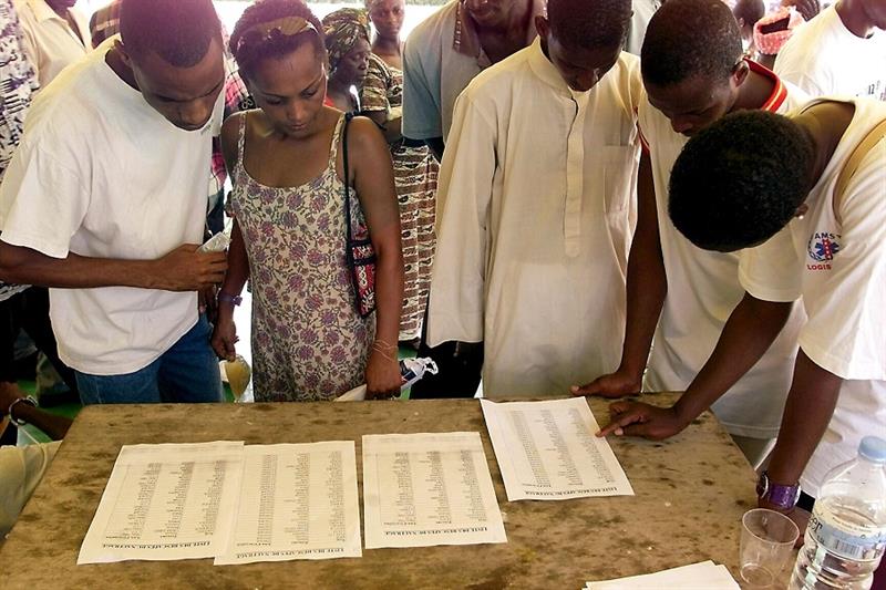 Bystanders look at a list of survivors in The City Hall of Dakar