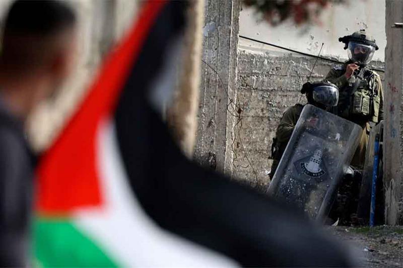 A Palestinian demonstrator waves a national flag during confrontations with Israeli troops, followin