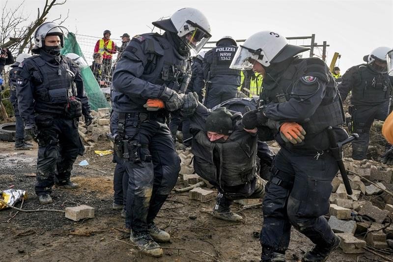 A protester is carried by police officers next to the Garzweiler lignite opencast mine at the villag