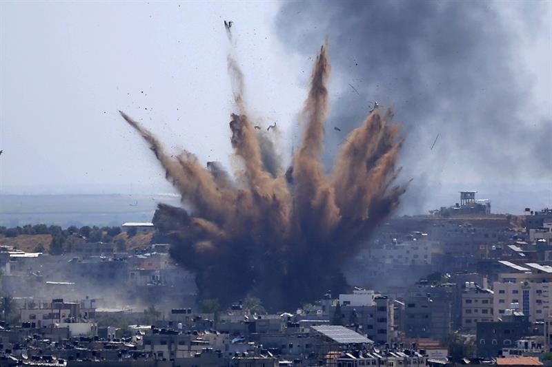 A blast from an Israeli airstrike on a building in Gaza City throws dust and debris