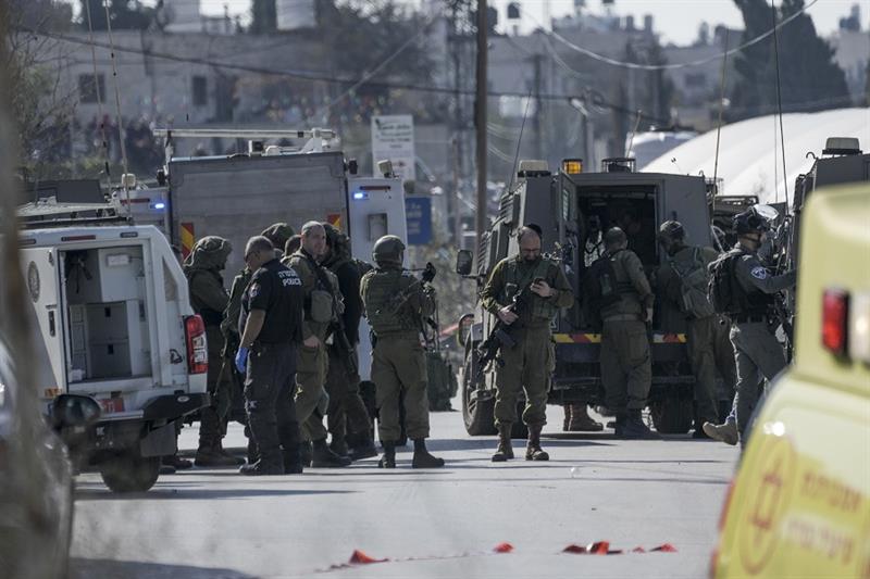 Israeli security forces examine the scene of a shooting in the West Bank town of Halhul