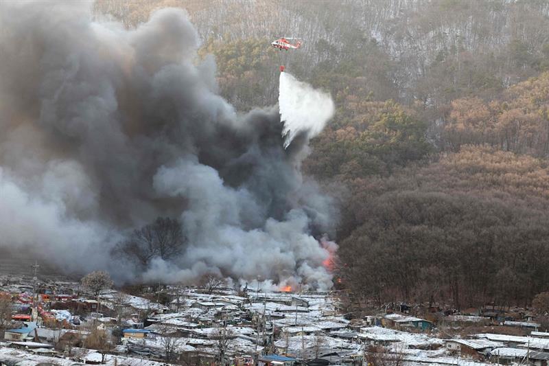 Firefighters try to extinguish a fire at the Guryong village, one of South Korea s last remaining sl
