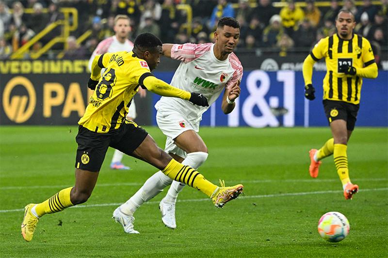 Dortmund s German forward Youssoufa Moukoko (L) has a shot next to Augsburg s German defender Felix 