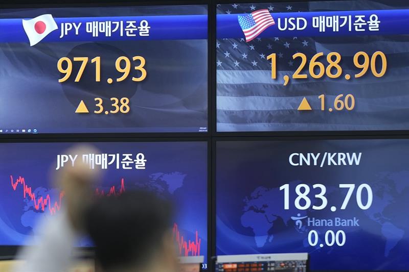 A currency trader walks by the screens showing the foreign exchange rates at a foreign exchange deal