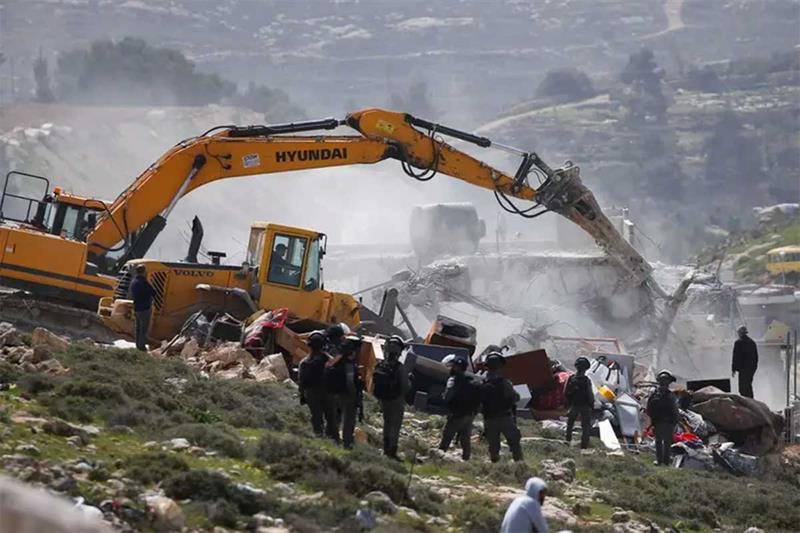 Israeli border policemen stand guard as an Israeli machinery demolishes a Palestinian structure, in 