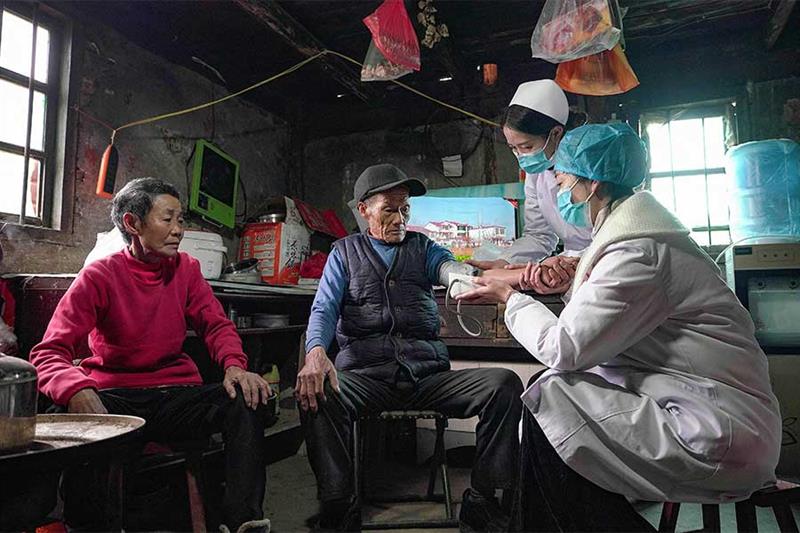This photo taken on January 3, 2023 shows a resident (C) receiving a health check in Danzhai county,
