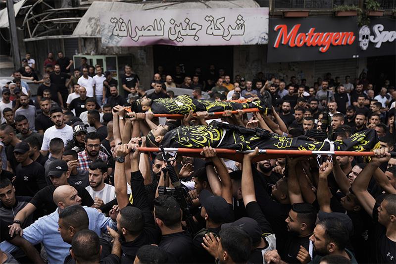 Palestinians, some armed, carry the bodies of Aysar al-Amer, 25, a local commander in the Islamic Ji