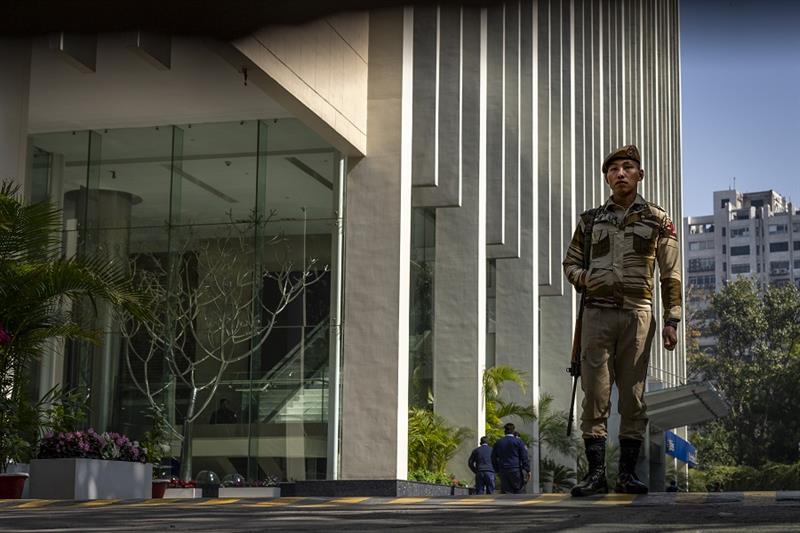 An armed security person stands guard at the gate of a building housing BBC office in New Delhi, Ind