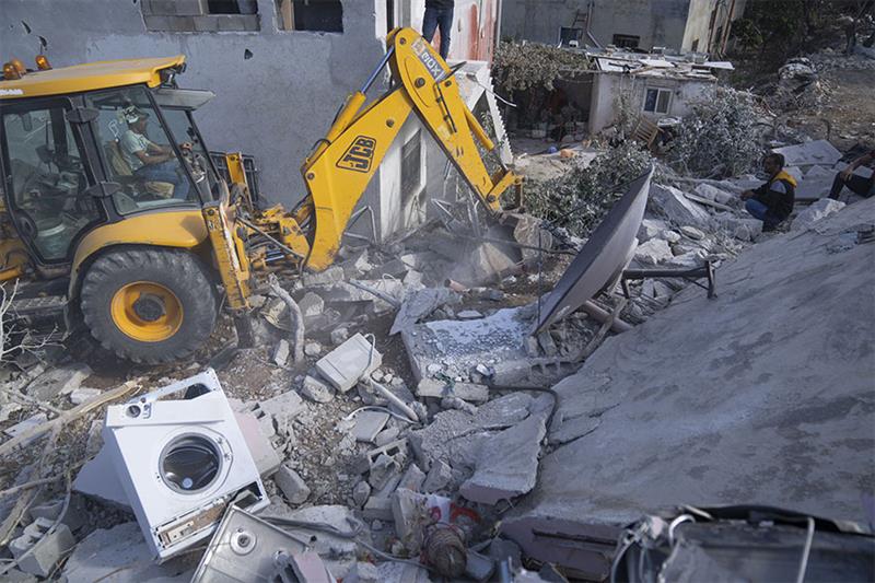A bulldozer clears the rubble at the site of the demolished family home of Saleh al-Arouri, in the W