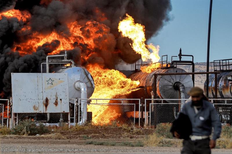 A man walks close to a fire raging at the Zarba oil facility in al-Qahtaniyah in northeastern Syria 