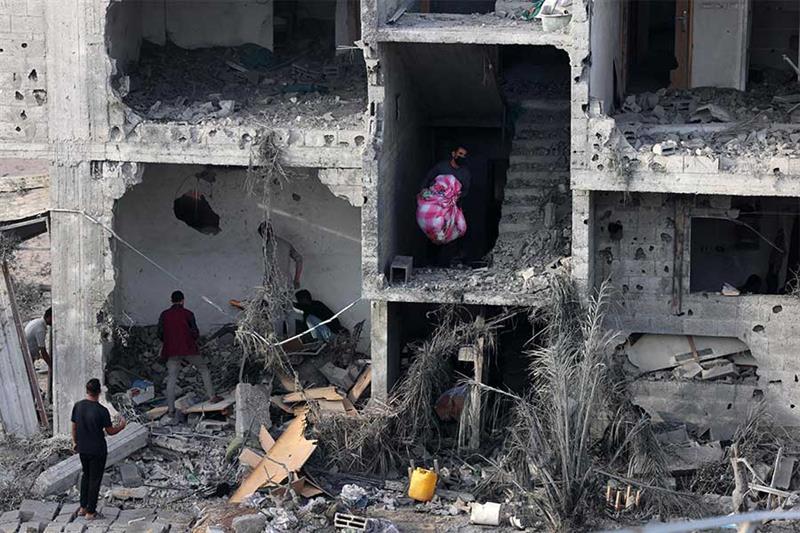 People salvage some belongings from a damaged building following Israeli bombing on Rafah in the sou