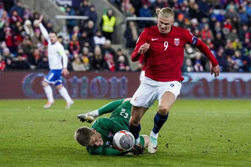 Norway s Erling Haaland, right, and Faroe Islands  goalkeeper Bardur a Reynatrod, left, challenge fo
