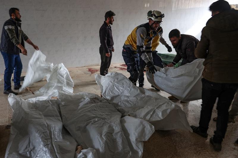 Residents and a rescuer from the Syrian White Helmets, pile up bodies of civilians killed in a Syria