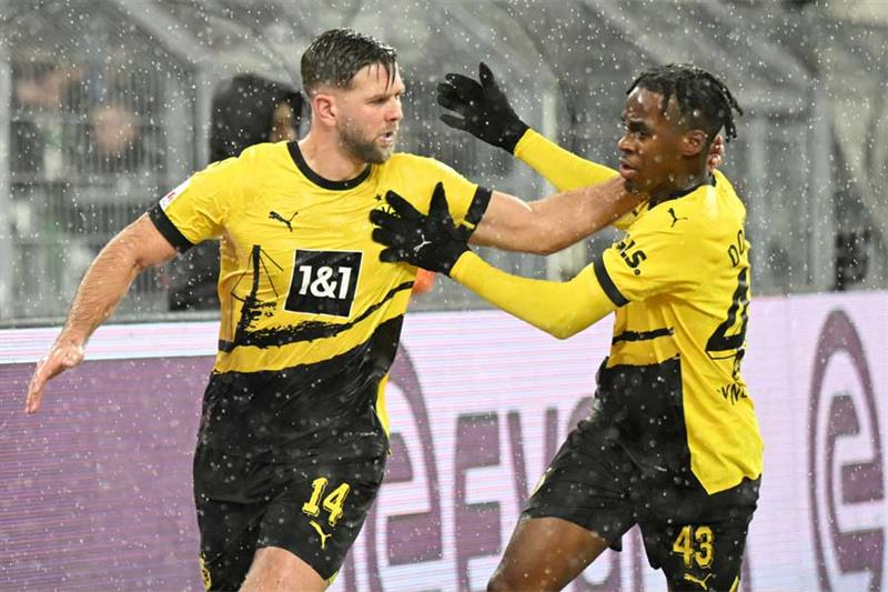 Dortmund s German forward #14 Niclas Fuellkrug (L) celebrates scoring the 2-2 goal with Dortmund s E