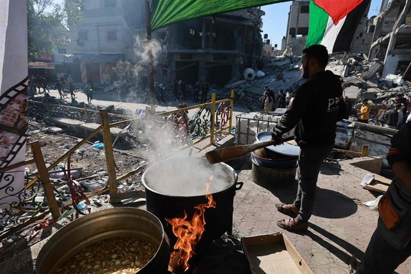 A Palestinian volunteer cooks at a spot offering charity food and bread donations in the southern Ga