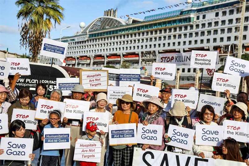 Travellers who were aboard Panama-flagged cruise ship  Pacific World  gather with signs in solidarit