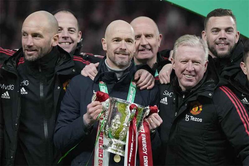 Manchester United s head coach Erik ten Hag, centre, and team members pose with the trophy after the