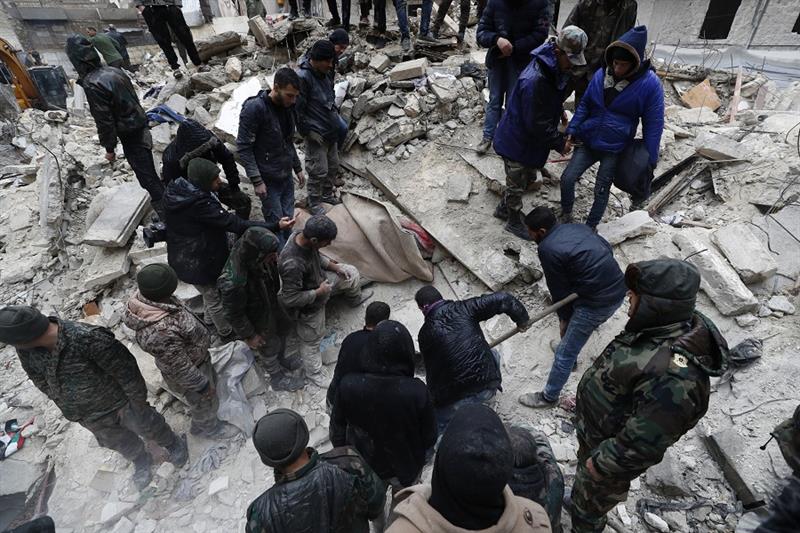 Syrian Civil Defense workers and security forces search through the wreckage of collapsed buildings,
