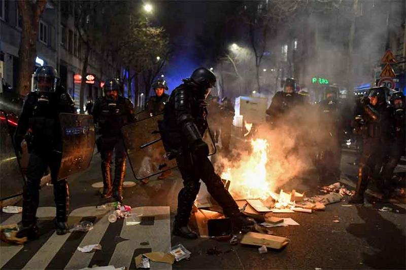A French Gendarme kicks a street fire during a demonstration in Paris, on March 18, 2023, against th
